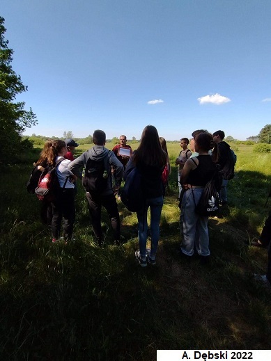 PhD student explaining to students in the field the issues of geomorphology at the geological profile